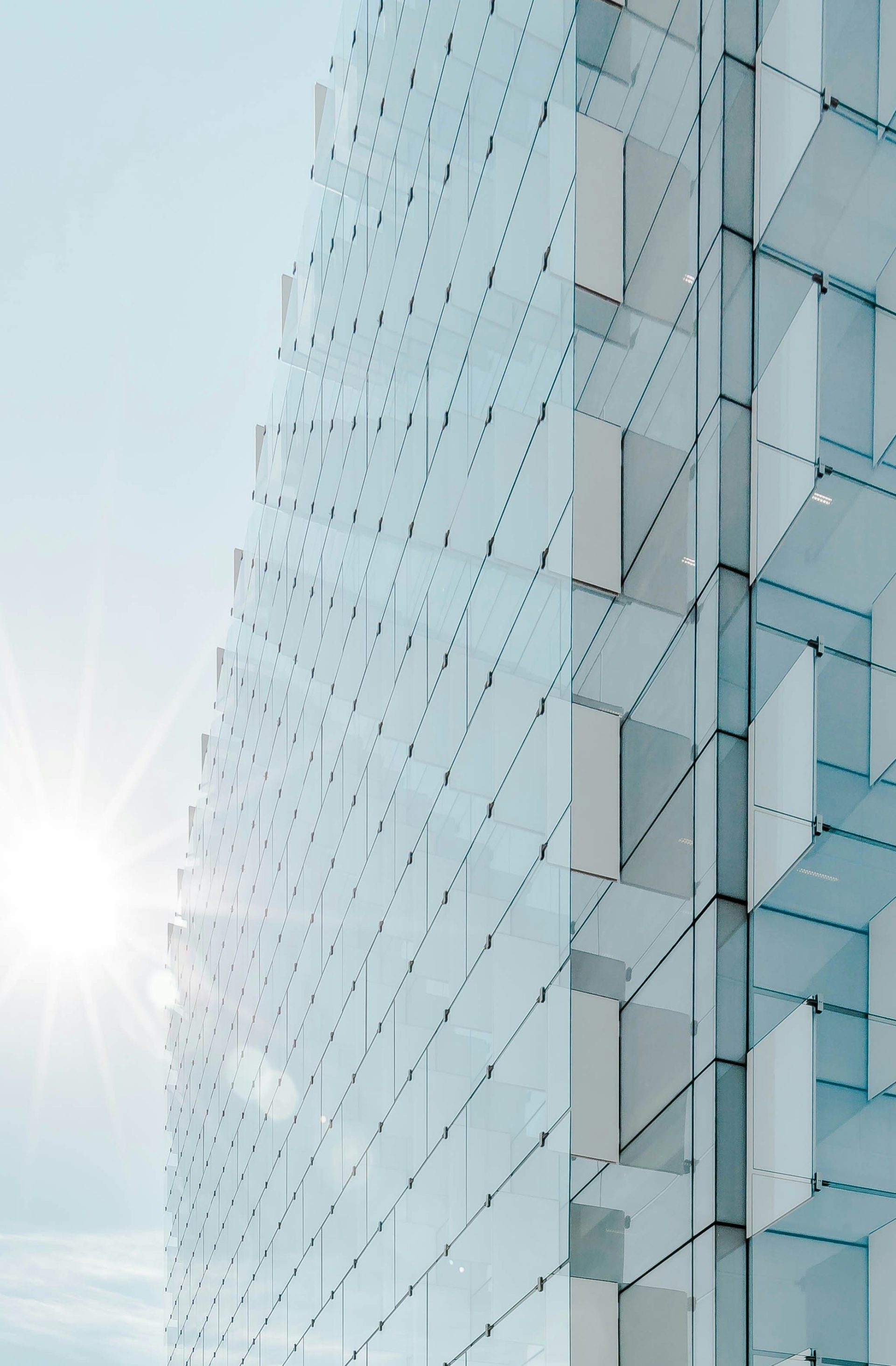 glass panel high-rise building under blue sky with sun raise